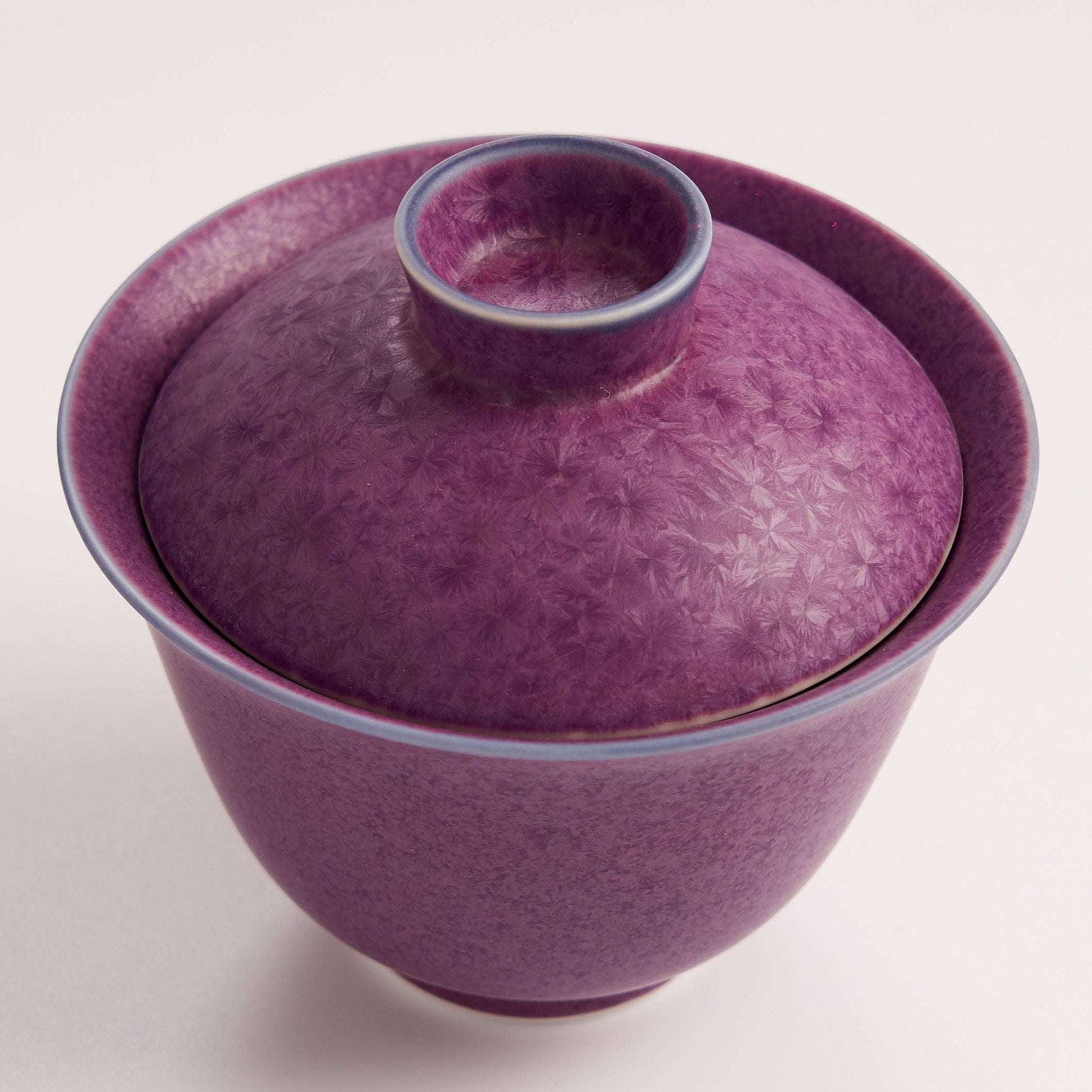 Purple ceramic bowl with a matching lid on a white background