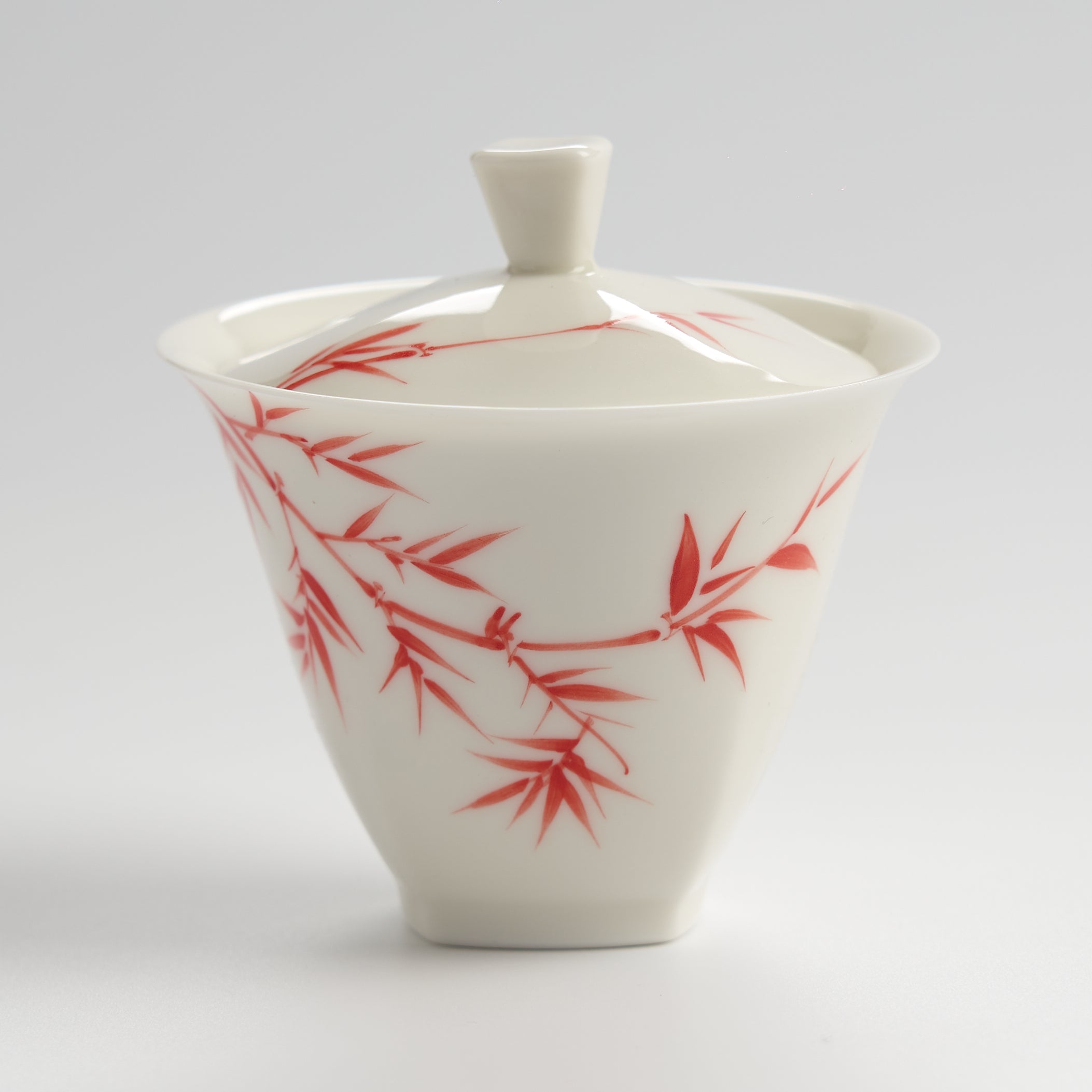 White ceramic container with red bamboo design on a gray background