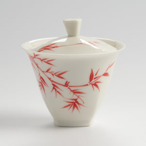 White ceramic container with red bamboo design on a gray background