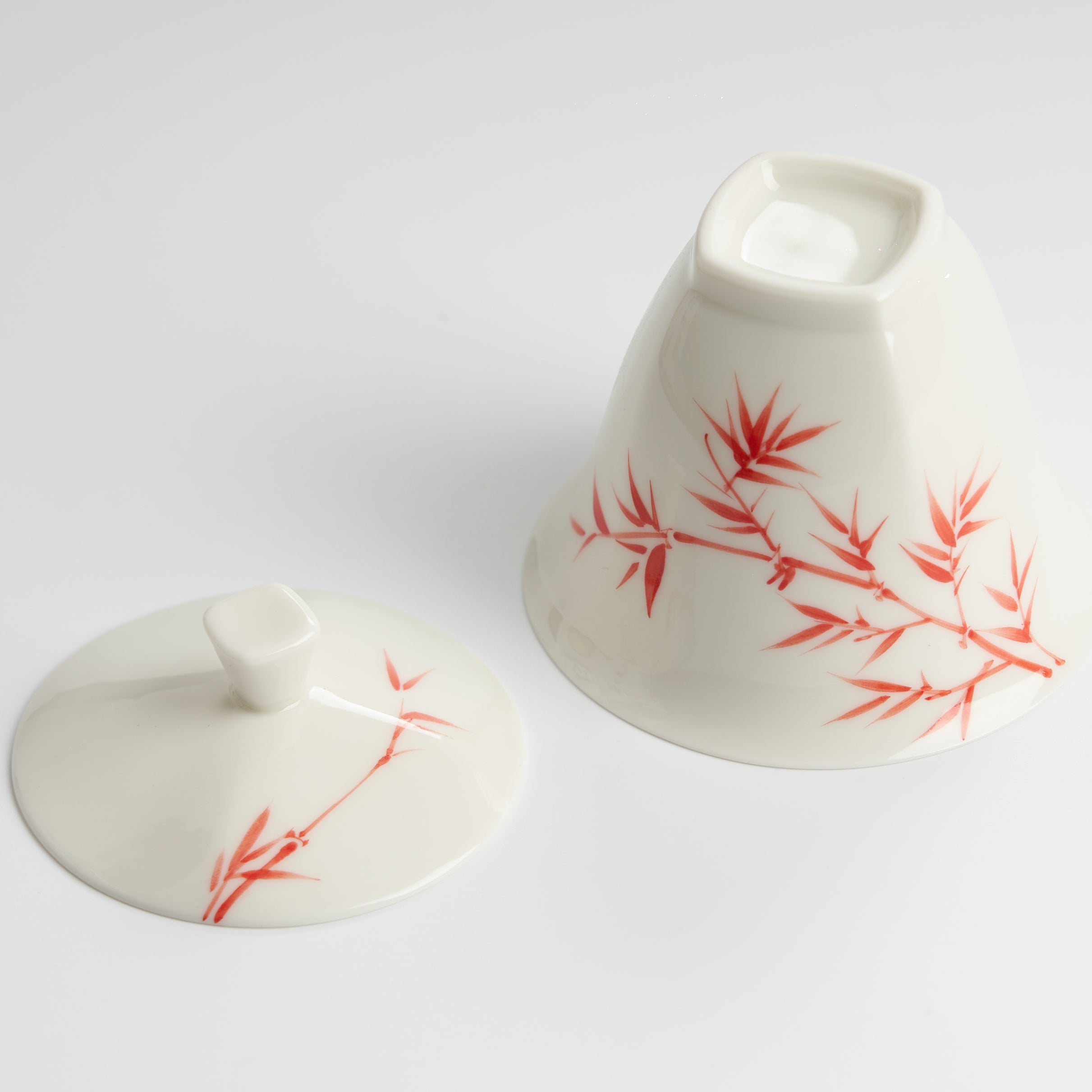 White ceramic container with red bamboo design on a white background