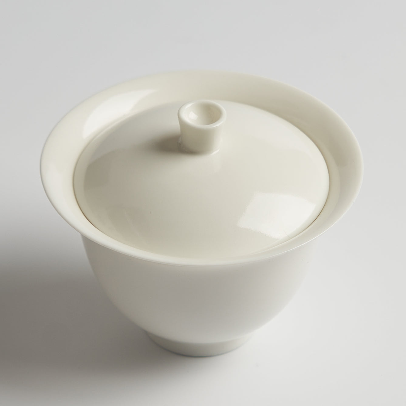 White ceramic container with lid on a light gray background