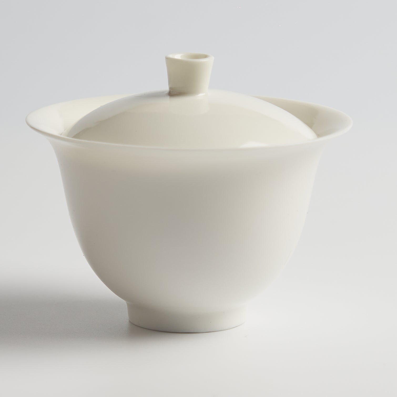 White ceramic teapot with lid on a light gray background