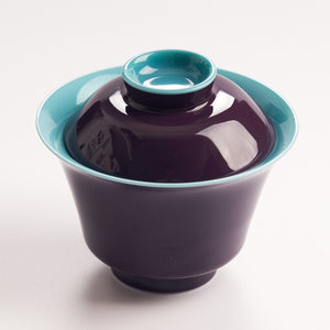 Purple ceramic teacup with a matching lid on a white background