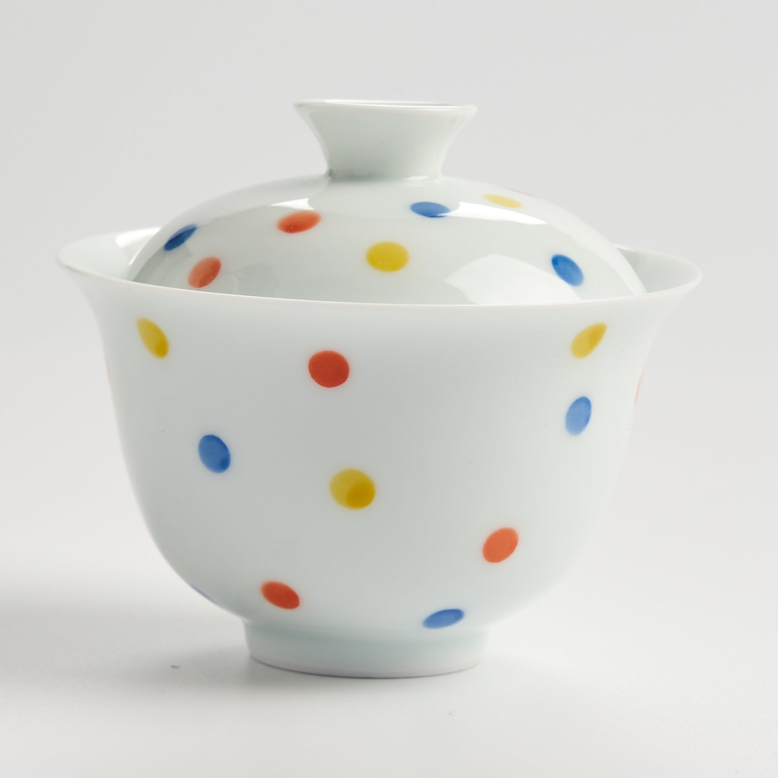 White ceramic bowl with colorful polka dots on a white background