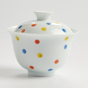 White ceramic bowl with colorful polka dots on a white background