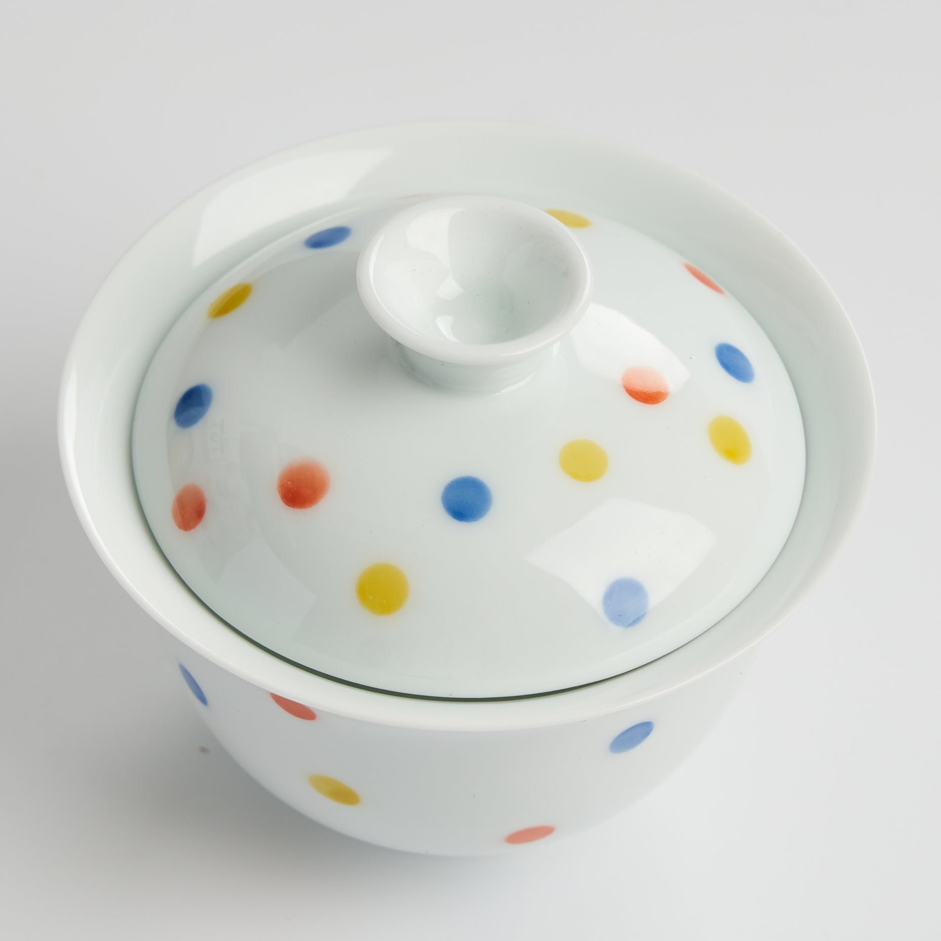 White ceramic container with colorful polka dot pattern on a white background