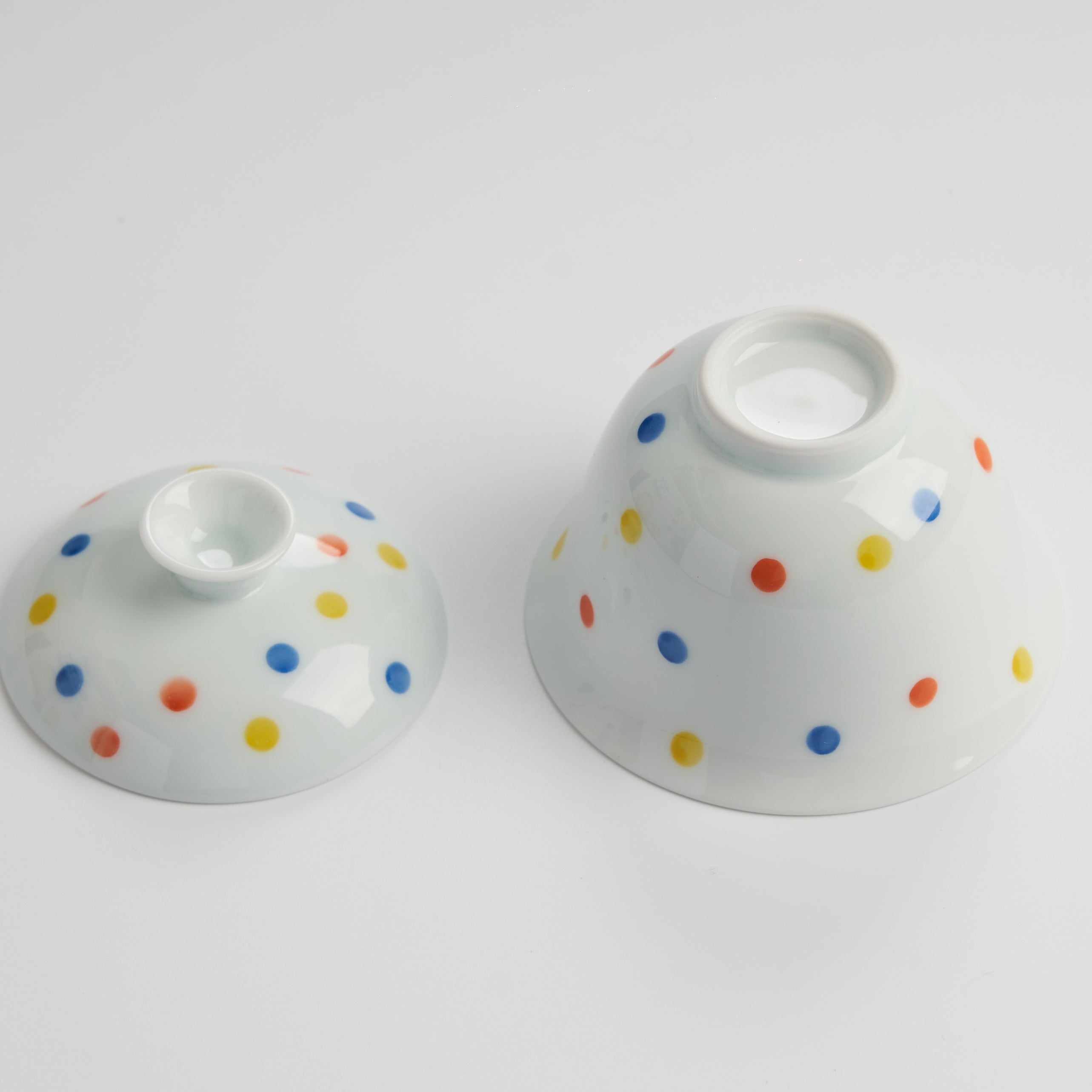 Two ceramic bowls with colorful polka dot patterns on a white background
