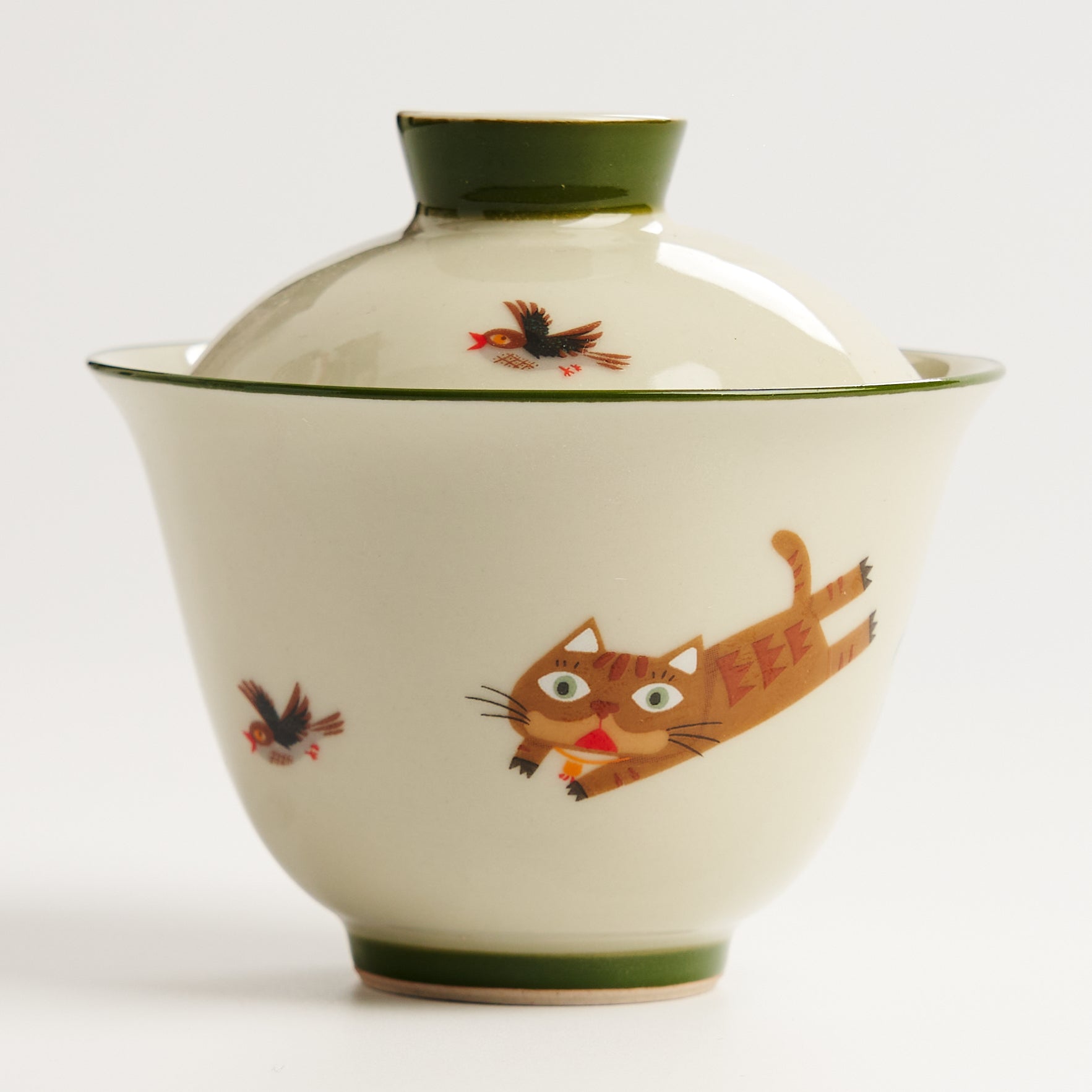 Ceramic bowl with a lid featuring illustrations of a cat and birds on a white background