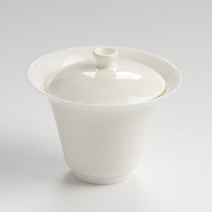 White ceramic teacup with lid on a light gray background
