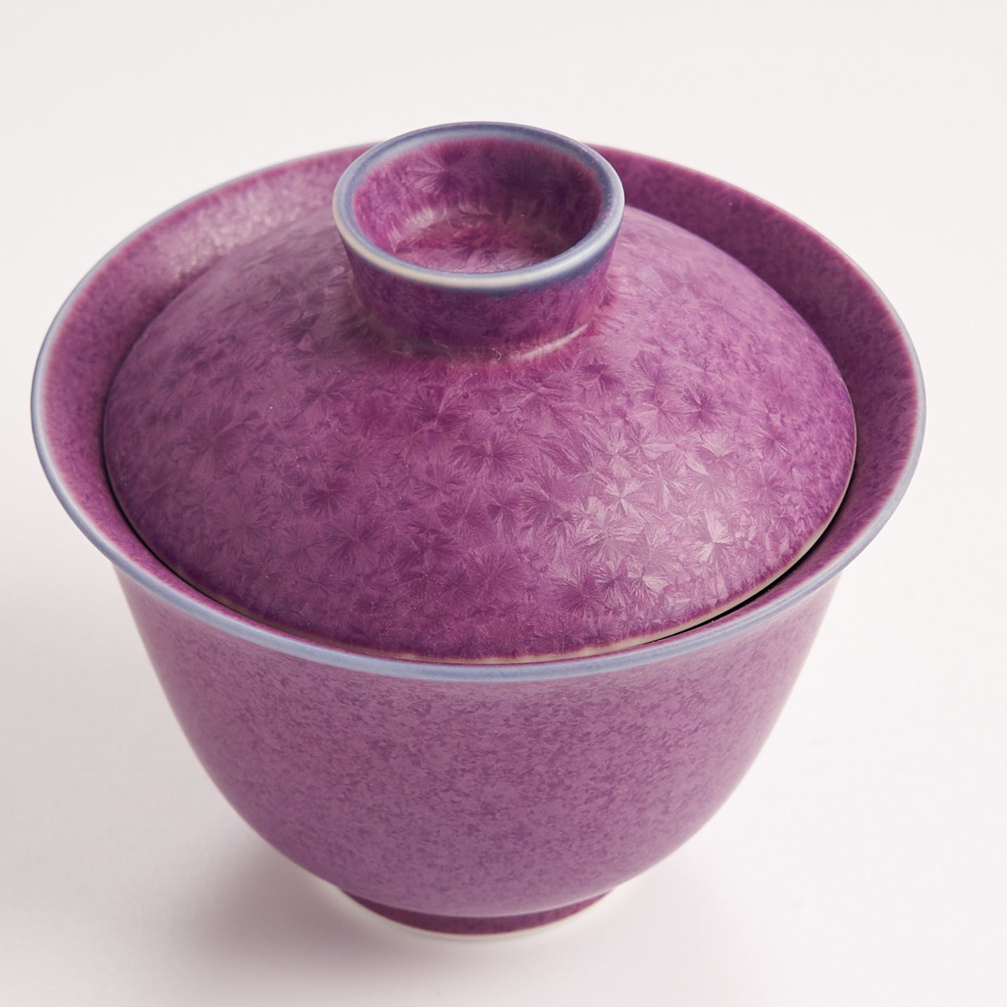 Purple ceramic bowl with cover on a white background