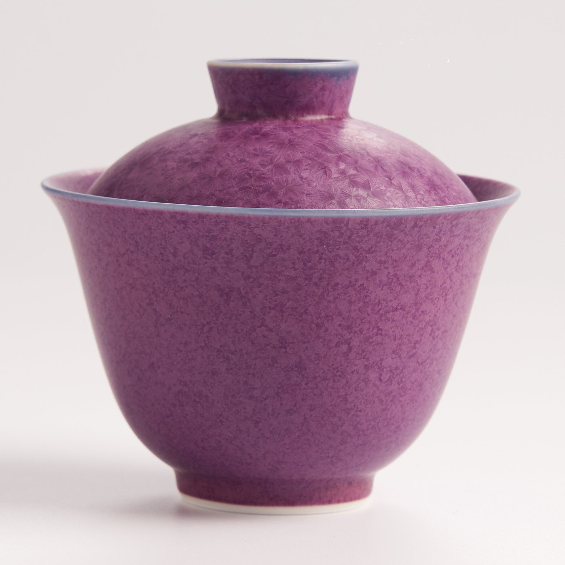 Purple ceramic teacup with lid on a white background