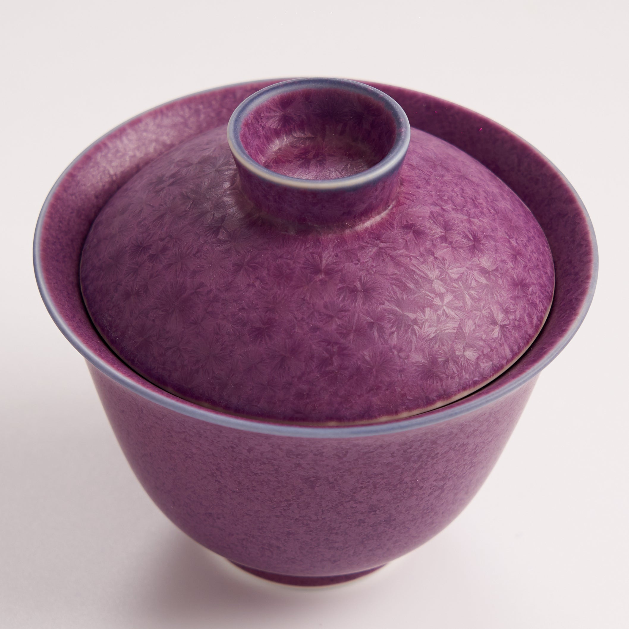 Purple ceramic bowl with a matching lid on a white background