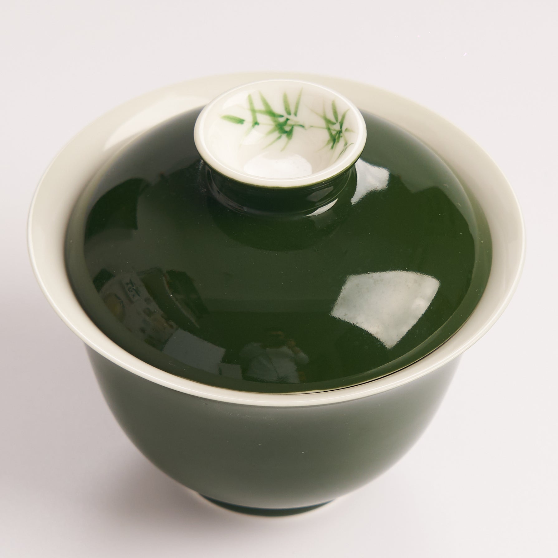 Green ceramic gaiwan with bamboo detailed lid on a white background