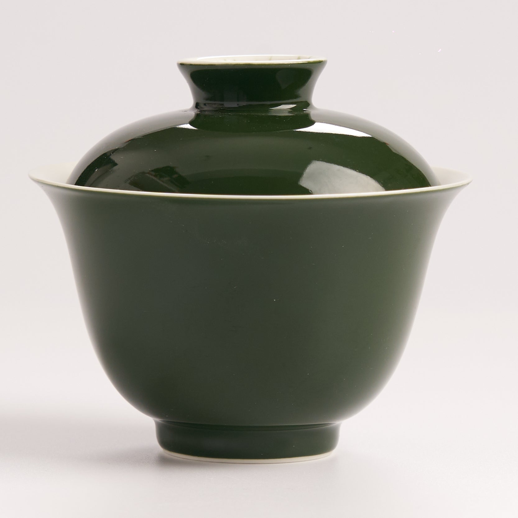 Side view of green ceramic gaiwan with lid on a white backgroundn