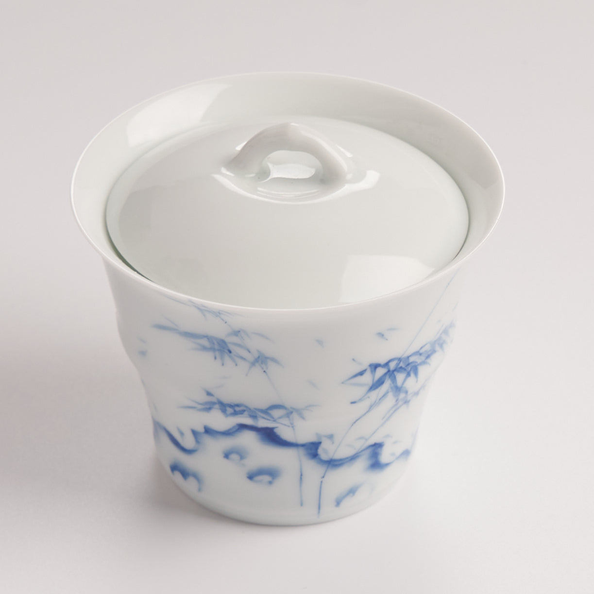 Top view of white porcelain gaiwan lid with smooth glaze and curved handle