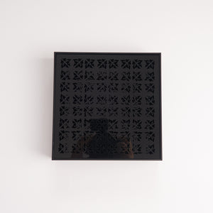 Black acrylic tea tray with geometric cutout surface, top view