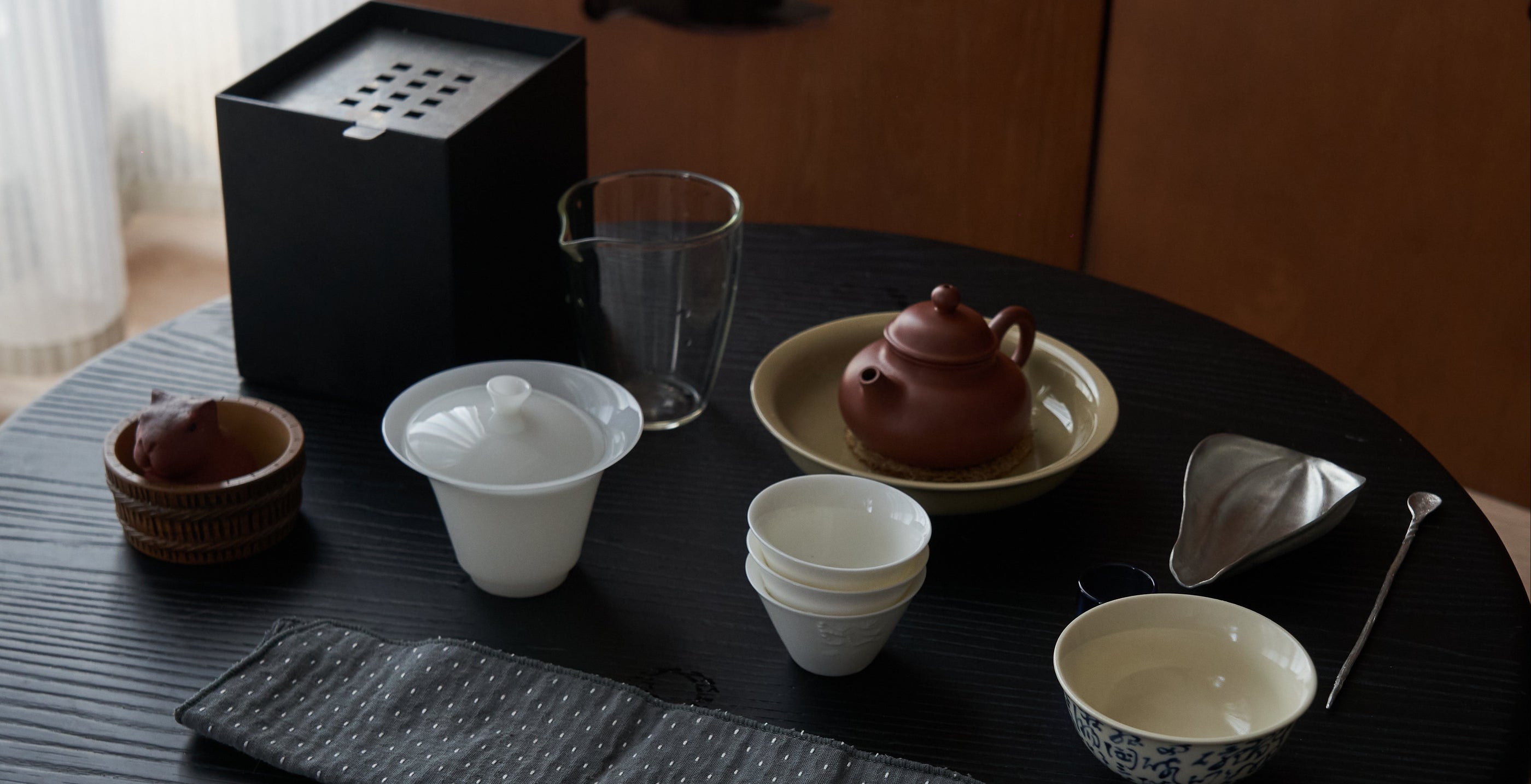 Tea-making set on a round black table with a blurred background
