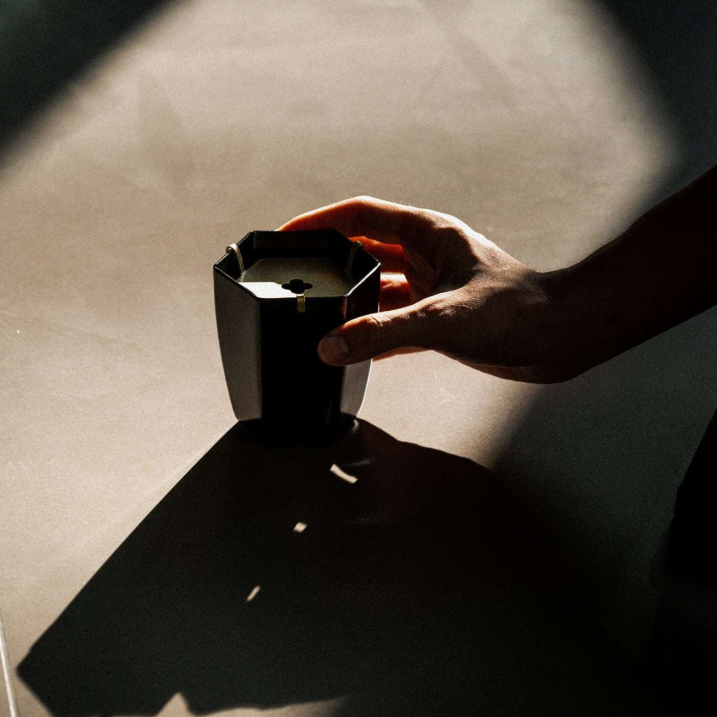 Hand holding black iron waste bowl