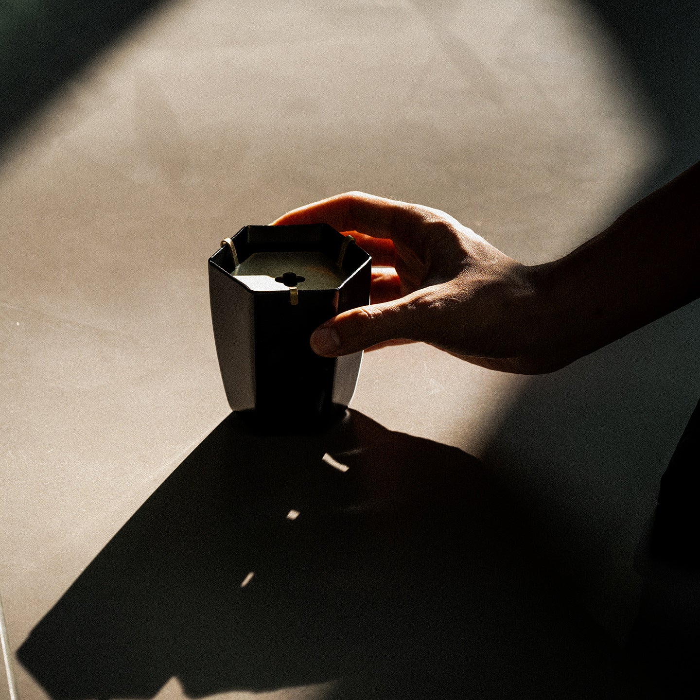 Hand holding black iron waste bowl