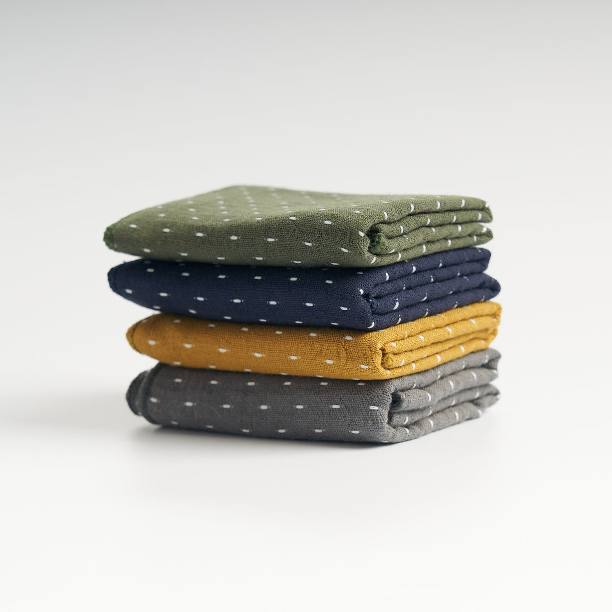 Thick cotton-linen tea towels in gray, yellow, blue, and green, stacked front view