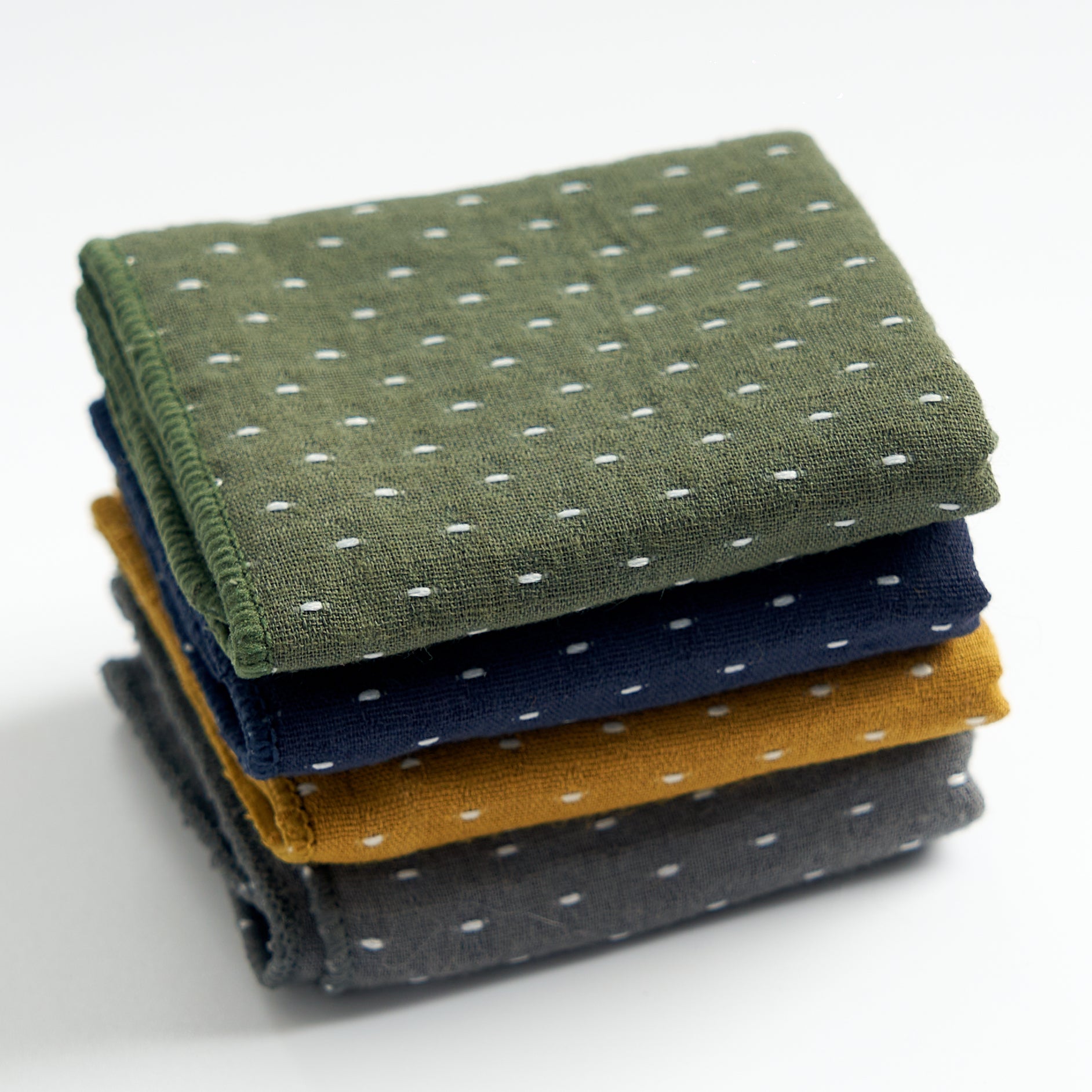 Thick cotton-linen tea towels in green, blue, yellow, and gray, slightly overhead view