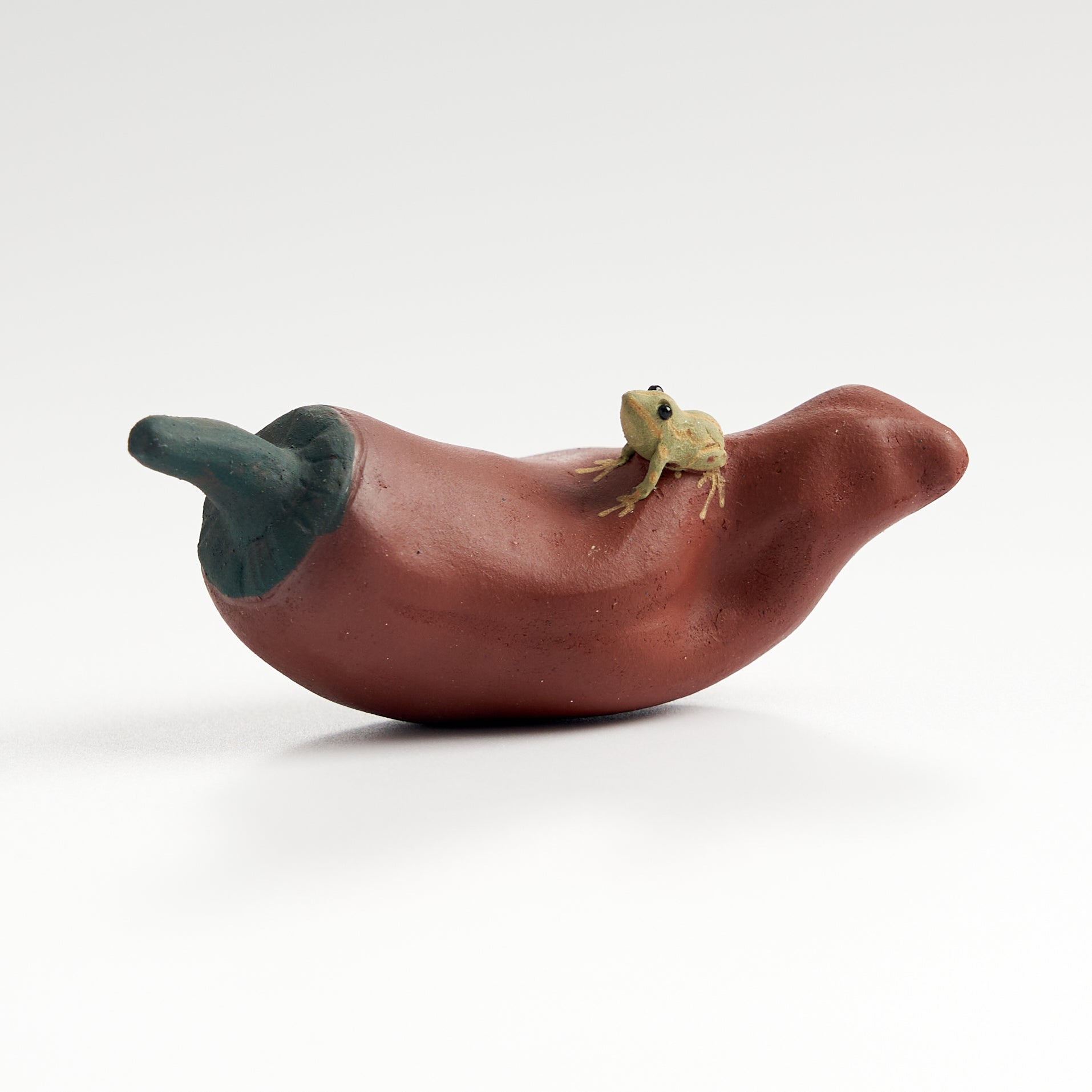 Handmade frog tea pet on a red chili pepper, front eye-level view