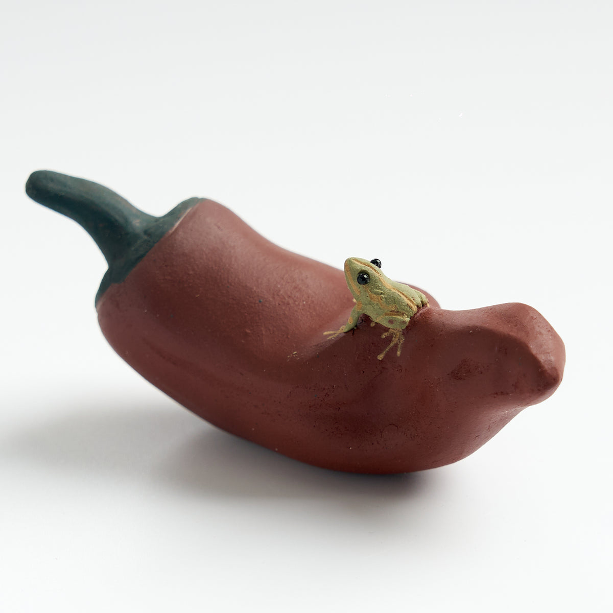 Handmade frog tea pet on a red chili pepper, three-quarter view