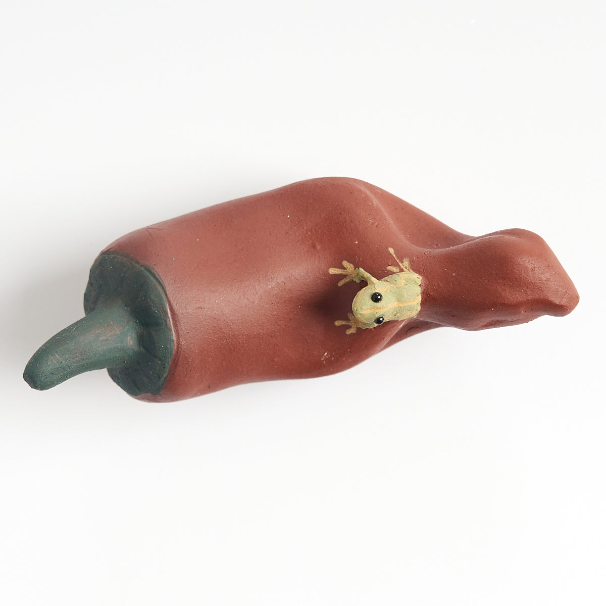 Handmade frog tea pet on a red chili pepper, top-down view