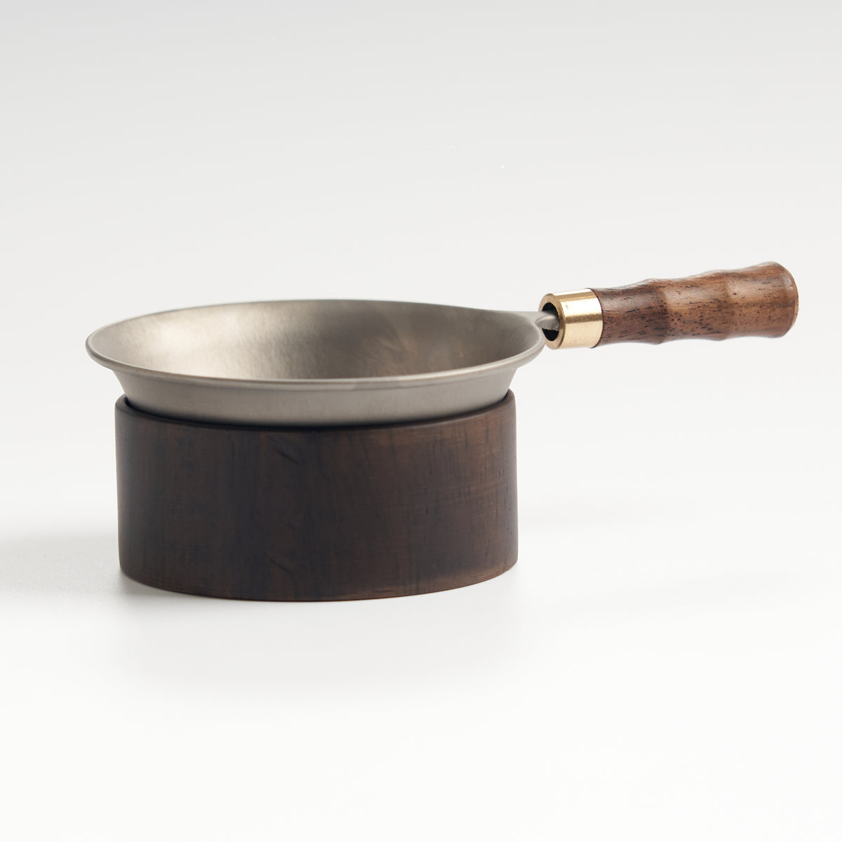 Stainless-steel tea strainer with wooden base, front eye-level view
