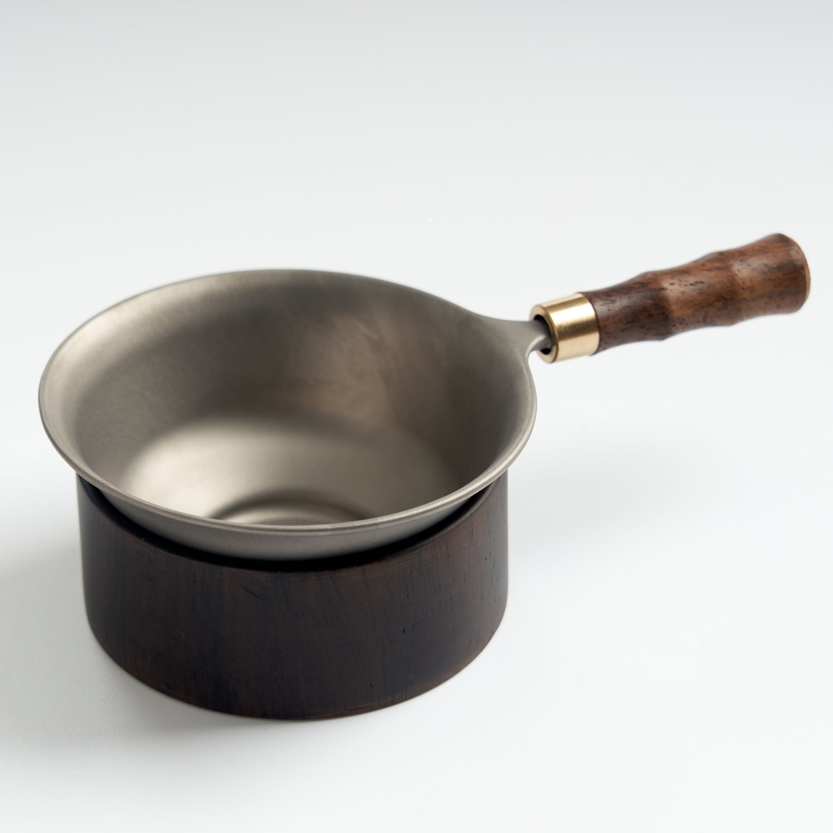 Stainless-steel tea strainer with wooden base, slightly overhead view
